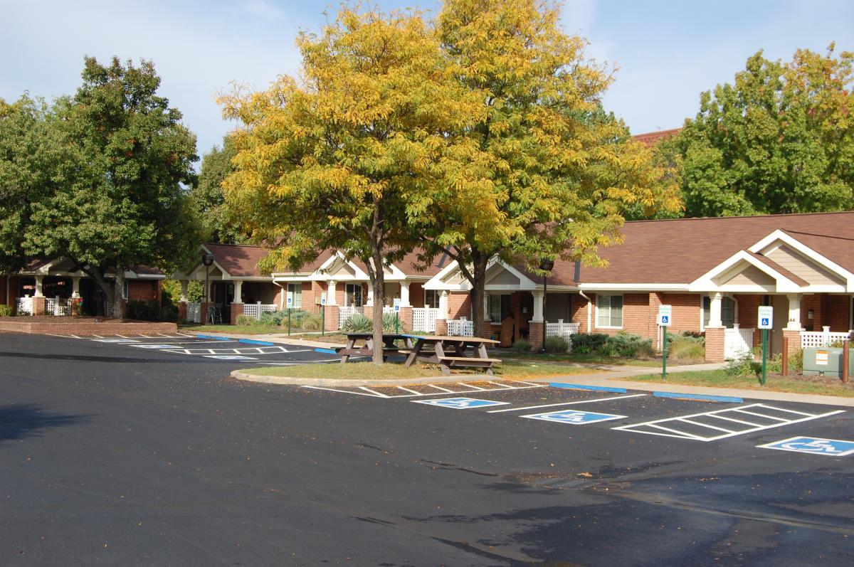 Single-story brick building with several accessible parking spaces and a tree with yellow leaves in front.